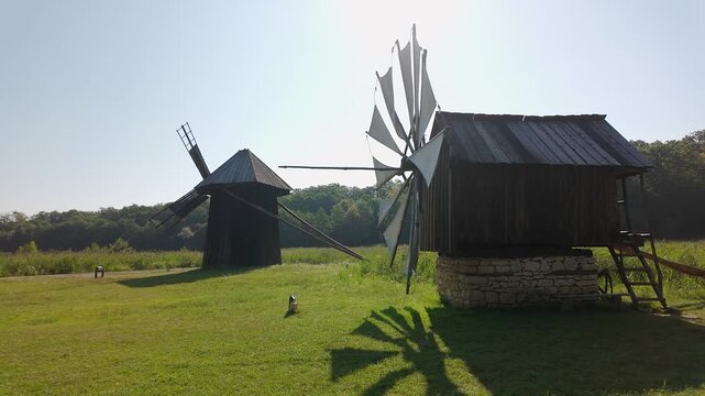 Traditional Romanian wooden windmills standing in a sunny grassy rural landscape