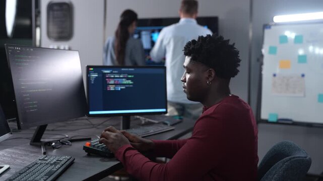 African male programmer coding on computer monitors in modern technology office, Software development, IT business startup, professional software engineer working on smart future digital innovations