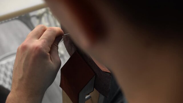 Leatherworker hand stitching brown genuine leather creating handmade accessories in a workshop