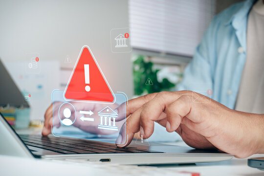 Hands typing on laptop keyboard with red warning exclamation triangle hologram icon and digital banking transfer security risk alert, cybersecurity threat, fraud prevention, and financial hacking.