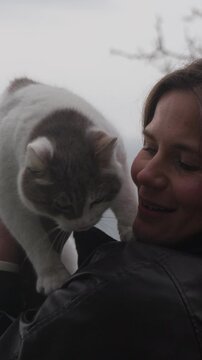 Cat woman outdoors woman holding and interacting with a grey and white cat in a tender moment under a cloudy sky