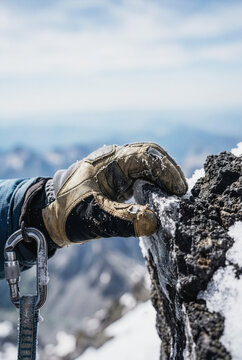 Climber hand gripping a snowy rock face