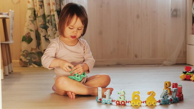 Young child playing on the floor with a colorful number train toy, exploring numbers through play.