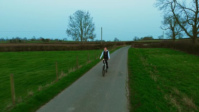 Cyclist woman riding bicycle along rural road at night with bright headlight, safe cycling visibility. Evening outdoor cardio workout burning fat calories, active cycling fitness training. Countryside