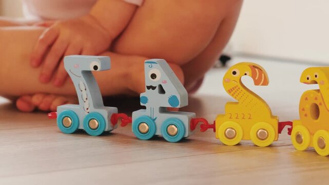 Young child arranges a colorful toy train shaped as numbers during educational play indoors.
