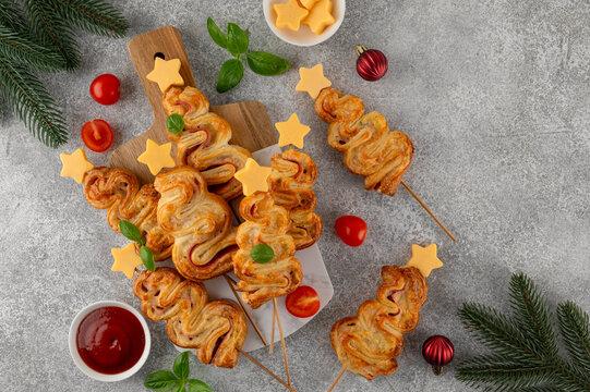Puff pastry Christmas tree buns with cheese and ham on a board. Christmas and New Year appetizer. Top view, copy space.