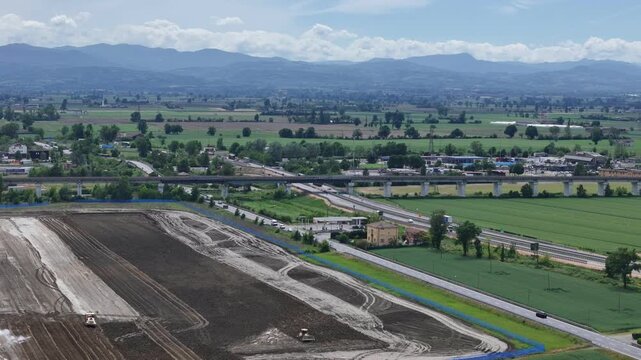 Large earthworks reshape farmland near Barabasca, Fiorenzuola d'Arda, Piacenza, Emilia-Romagna, Italy, beside A1, A21 and SS9 with Northern Apennines beyond, drone lateral pan.