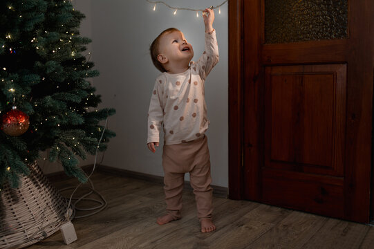 A small child touches electrical wires from a Christmas tree. Children without adult supervision. Electrical injuries, without parental supervision. Unpleasant incident on New Year's Eve.