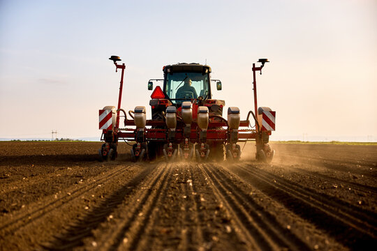 Farmer seeding field with modern tractor, planting seeds for agricultural crop growth