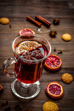 mulled wine with spices in cup on wooden background