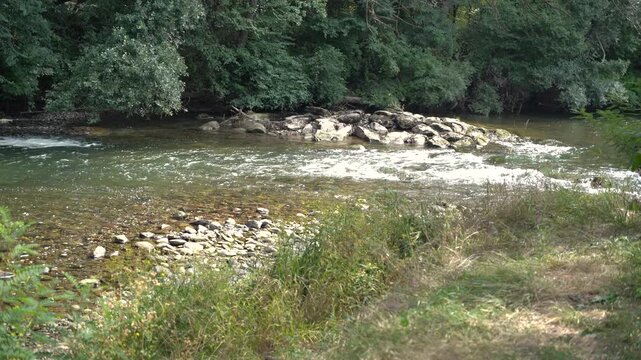 River rapidly flowing over the stone cascade in the forest