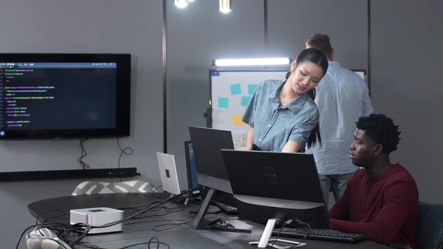Diverse IT technology team driving corporate digital transformation in modern offices. Asian female manager and African American programmer discussing the software system integration at the work desk