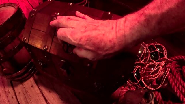 Treasure chest on ship's deck is opened with right hand. Point-of-view-shot.