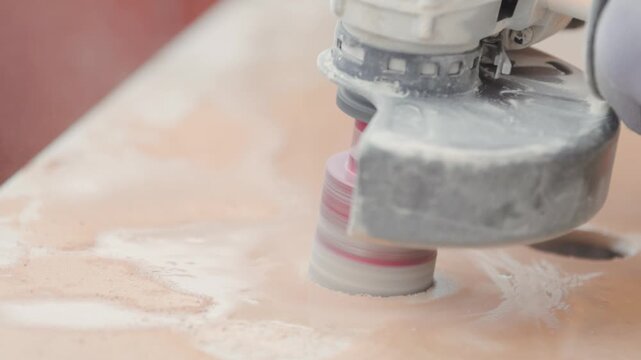 Close up of a power tool cutting holes in a ceramic tile. Circular cutter.