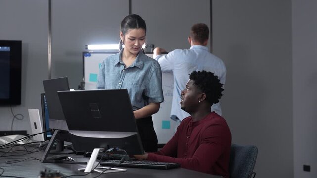 Diverse IT technology team driving corporate digital transformation in modern offices. Asian female manager and African American programmer discussing the software system integration at the work desk