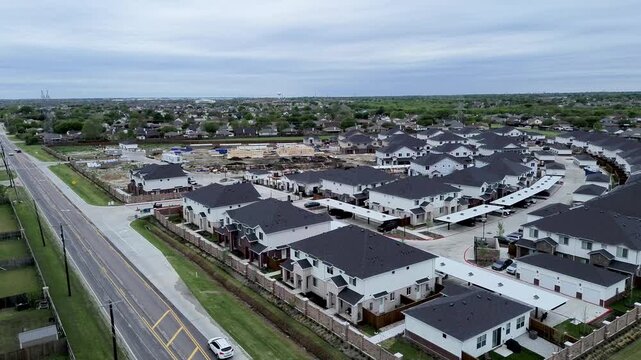 Wood framing structures rise beside Mansfield Webb Road near Yardly Eden residences. Carport canopies, paved drive aisles, utility posts highlight master planned living, Arlington, Texas