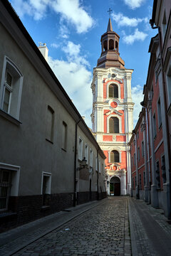 Narrow, cobbled street and the bell tower of a Baroque church in Poznan