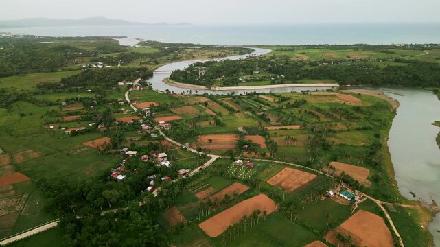Scenic aerial drone shot across the winding Pajo River, cultivated fields, and scattered barangay homes - Catanduanes, Bicol, Philippines