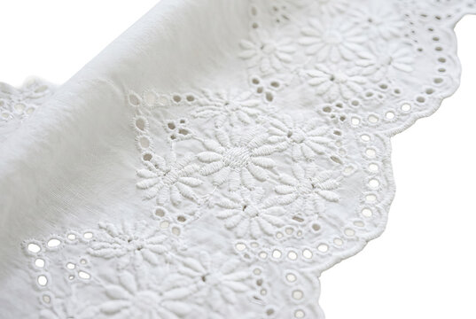 Close-up of delicate white eyelet fabric with floral embroidery.