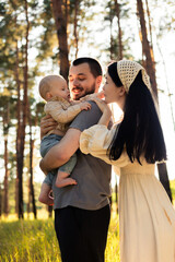 Fototapeta premium Happy family with baby enjoying a sunny day in a pine forest