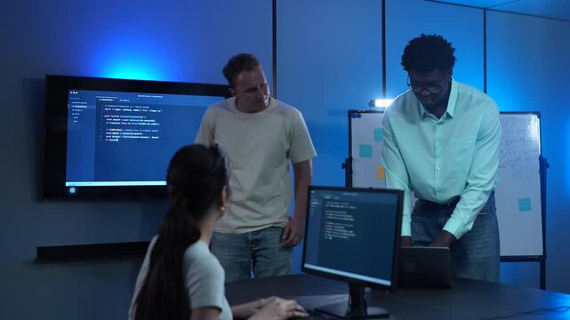 Diverse software developer team collaborating on computer code in modern IT office, Male programmers and female colleague brainstorming future technology business innovations and smart digital system