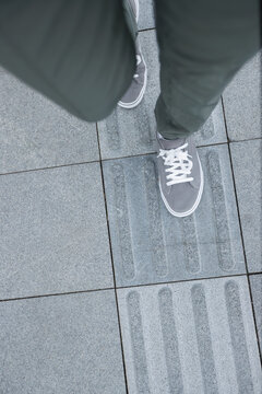  POV of legs walking in sneakers in the city tactile paving