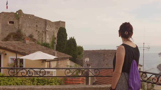 Woman enjoying a scenic view of the medieval castle of Roquebrune Cap Martin, France
