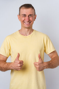 Smiling man giving two thumbs up, showing approval, confidence and success in a studio portrait against a clean white background, conveying happiness and motivation
