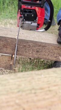 Wood cutting process in a workshop using a chainsaw on a wooden log