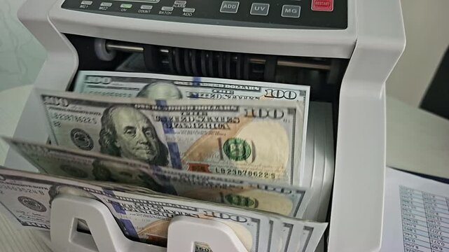 Counting money with a machine at a bank in the city during daylight hours