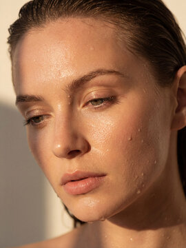 Beauty portrait of young woman with wet hair and clean dewy skin in natural warm light