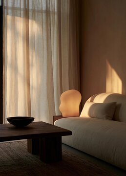 Modern living room with a large window on the left side. the window is covered with sheer white curtains that are open, allowing natural light to enter the room.