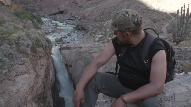 A man rests while gazing at the enormous Sipia Falls in the Cotahuasi Canyon in Peru.