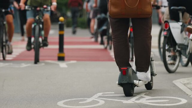 Cyclist riding along designated urban bike lane with prominent bicycle road markings and red pavement at crossing, modern cycling infrastructure, active mobility and sustainable transportation