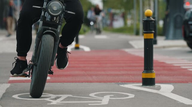 Close-up slow motion cyclist riding designated urban bike lane with prominent bicycle road markings and red pavement at crossing, modern cycling infrastructure, active mobility and transportation