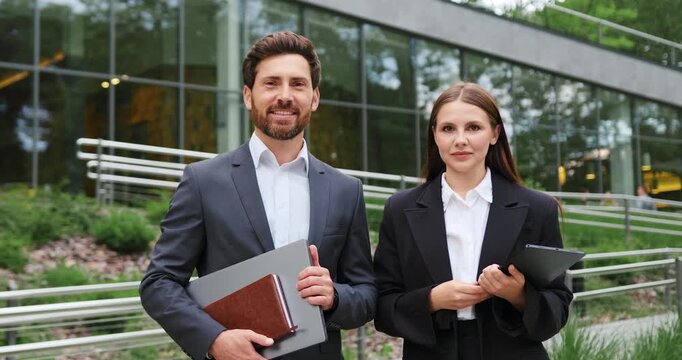Confident business colleagues man and woman looking at camera outdoors