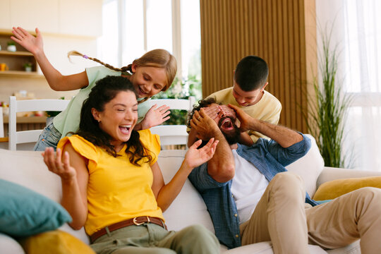 Family playing and laughing together on the sofa at home