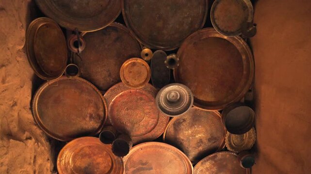Cinematic overhead top down shot of vintage copper trays and pots decorating mud wall in AlUla Old Town Saudi Arabia