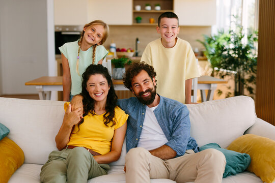 Smiling parents and children posing together in a bright home