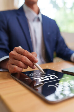 Businessman uses a stylus on a digital tablet showing 2027, representing New Year planning, business strategy, fresh goals, transformation, future growth, renewal and professional progress.