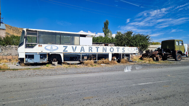 Stripped-out LAZ-4207 bus wreck with "Zvartnots" lettering and an old truck by the roadside in Talin; vintage Soviet bus, abandoned site, Aragatsotn, Armenia 28.08.2025