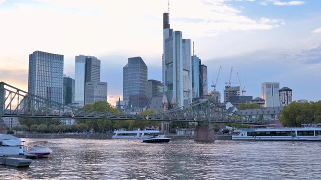 Frankfurt skyline with Eiserner Steg bridge over Main river at sunset.