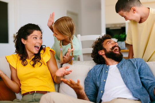 Happy parents laughing with children during family time at home