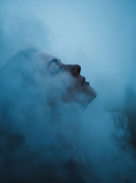Ethereal profile of a human face obscured by swirling blue mist.