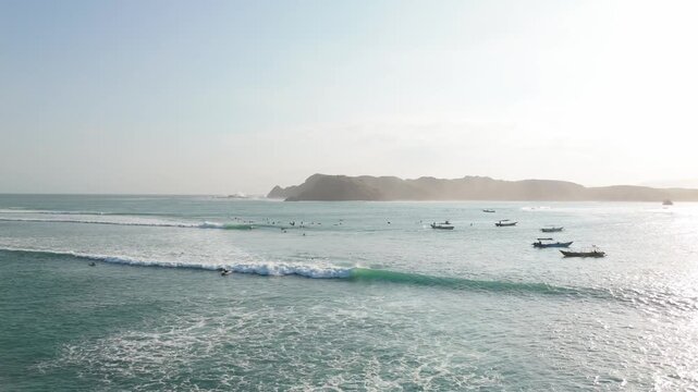 Aerial view of surf bay with traditional boats at anchor and headland in Kuta Lombok Indonesia