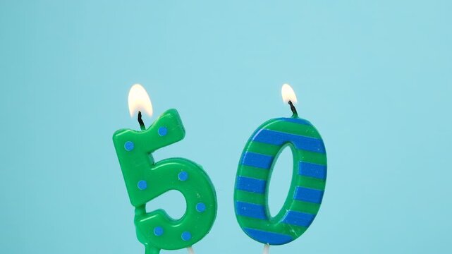 Number 50 birthday candles burning and gradually extinguishing against a clean light blue background, symbolizing a fiftieth birthday celebration and anniversary milestone.