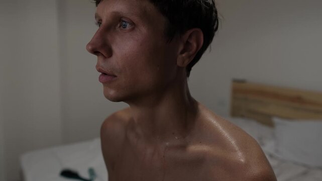 Overheated sweating man feeling exhausted and uncomfortable in hot room, perspiring heavily from summer heat and high indoor temperature