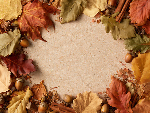 Autumn leaves and acorns surround a blank space on a textured background