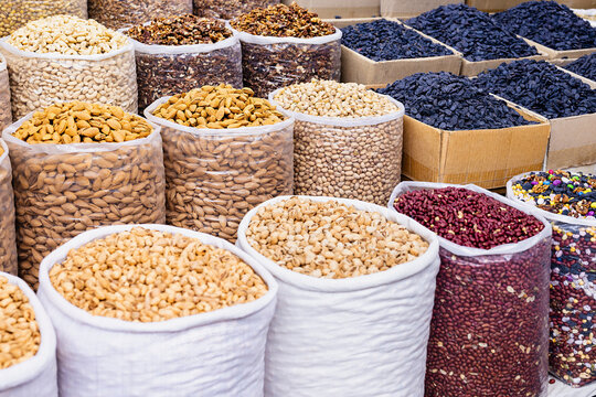 Dried fruits, nuts, beans, and legumes displayed in bulk sacks at an oriental bazaar in Bukhara, Uzbekistan. Ideal for food industry, travel, or cultural content.