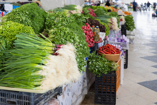 Fresh herbs and vegetables displayed at an oriental bazaar in Bukhara, Uzbekistan. Bunches of green onions, dill, cilantro, and red chili peppers fill market stalls. Ideal for travel, food culture.